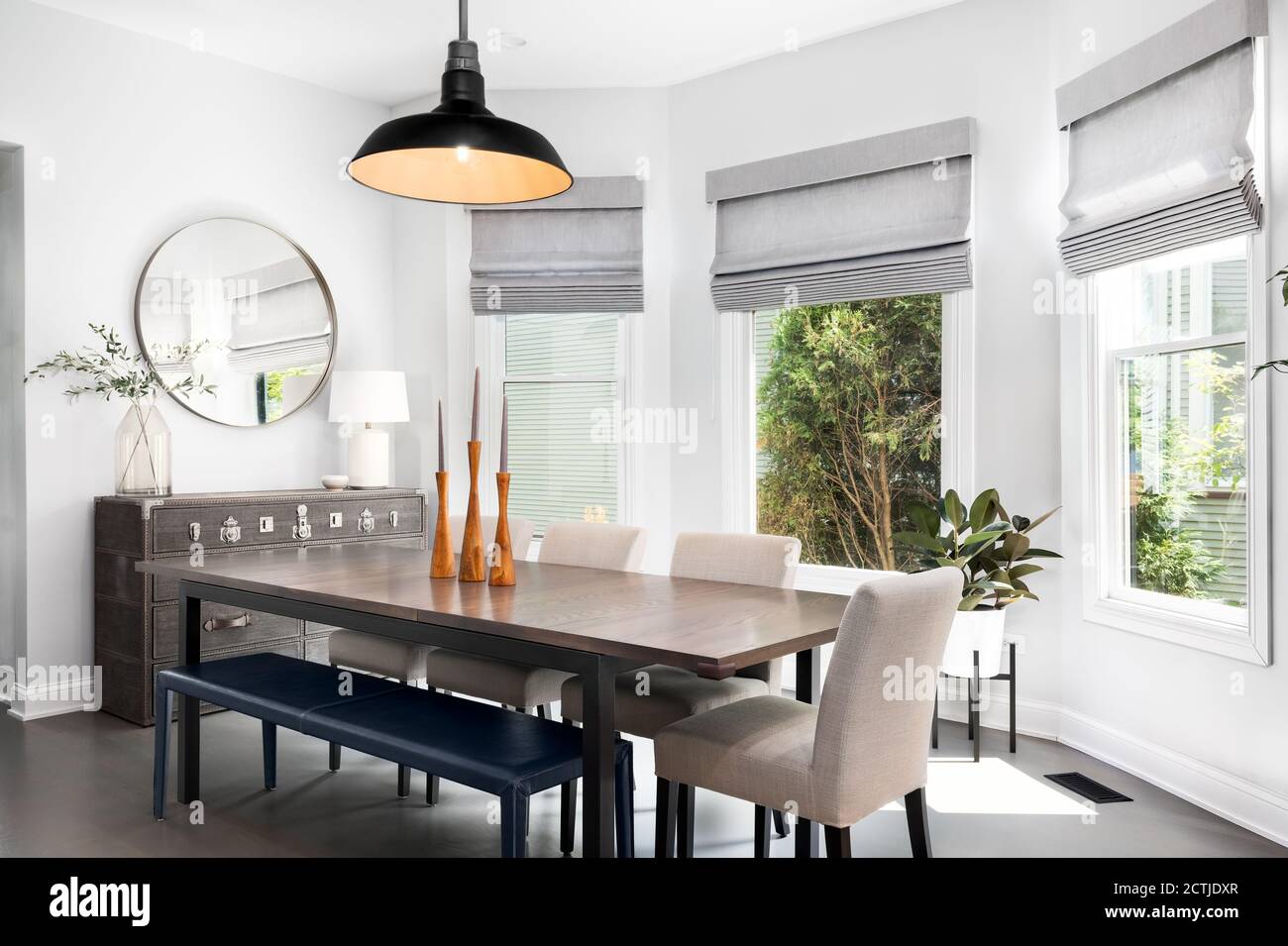 A Modern Living Room With A Large Table Bench Seat And Chairs A Hanging Light And A Dresser With A Mirror Over It Stock Photo Alamy