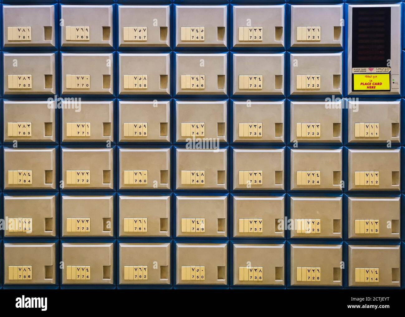 Multiple rows of golden post office boxes with numbers in Arabic and English and card reader close up view Stock Photo