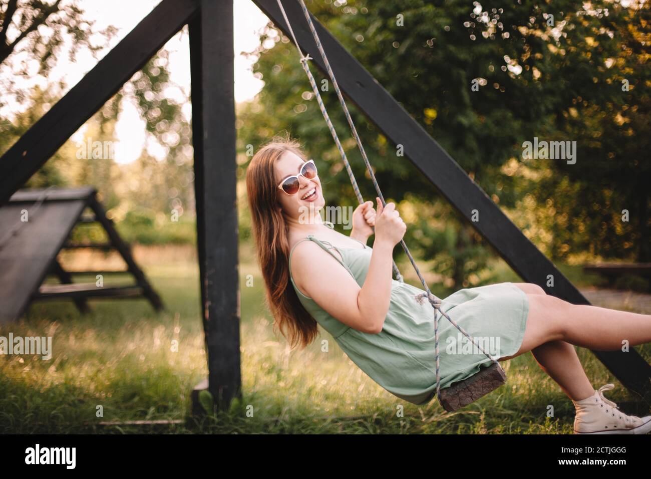 Happy young woman swinging in park during summer Stock Photo