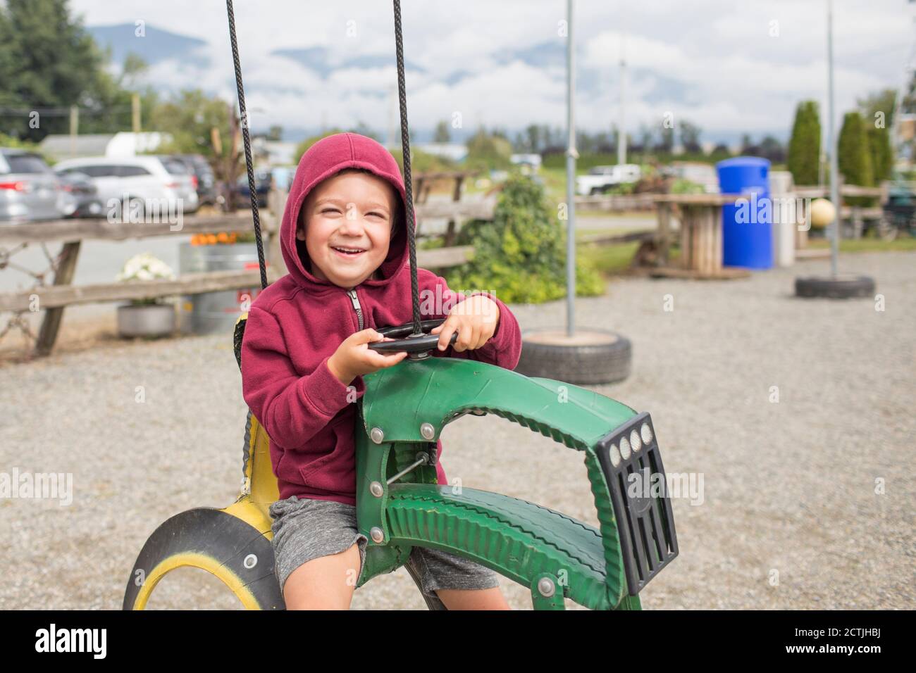 boy sits on play ride on tractor at farm made from recycled tires Stock Photo