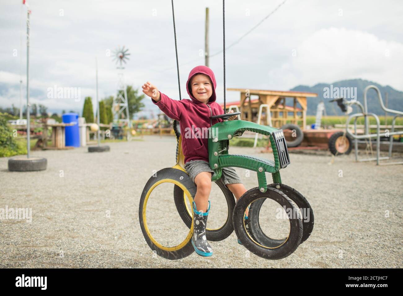 Young boy sits on play ride on tractor at farm made from recycled tire