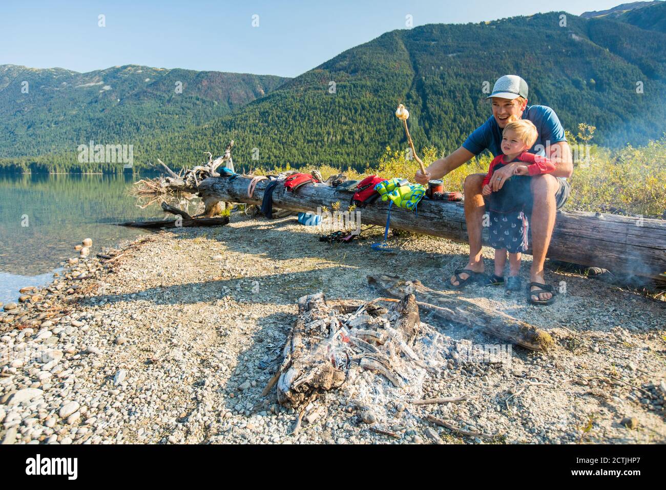Father and son roast marshmallows over fire during a father son trip Stock Photo