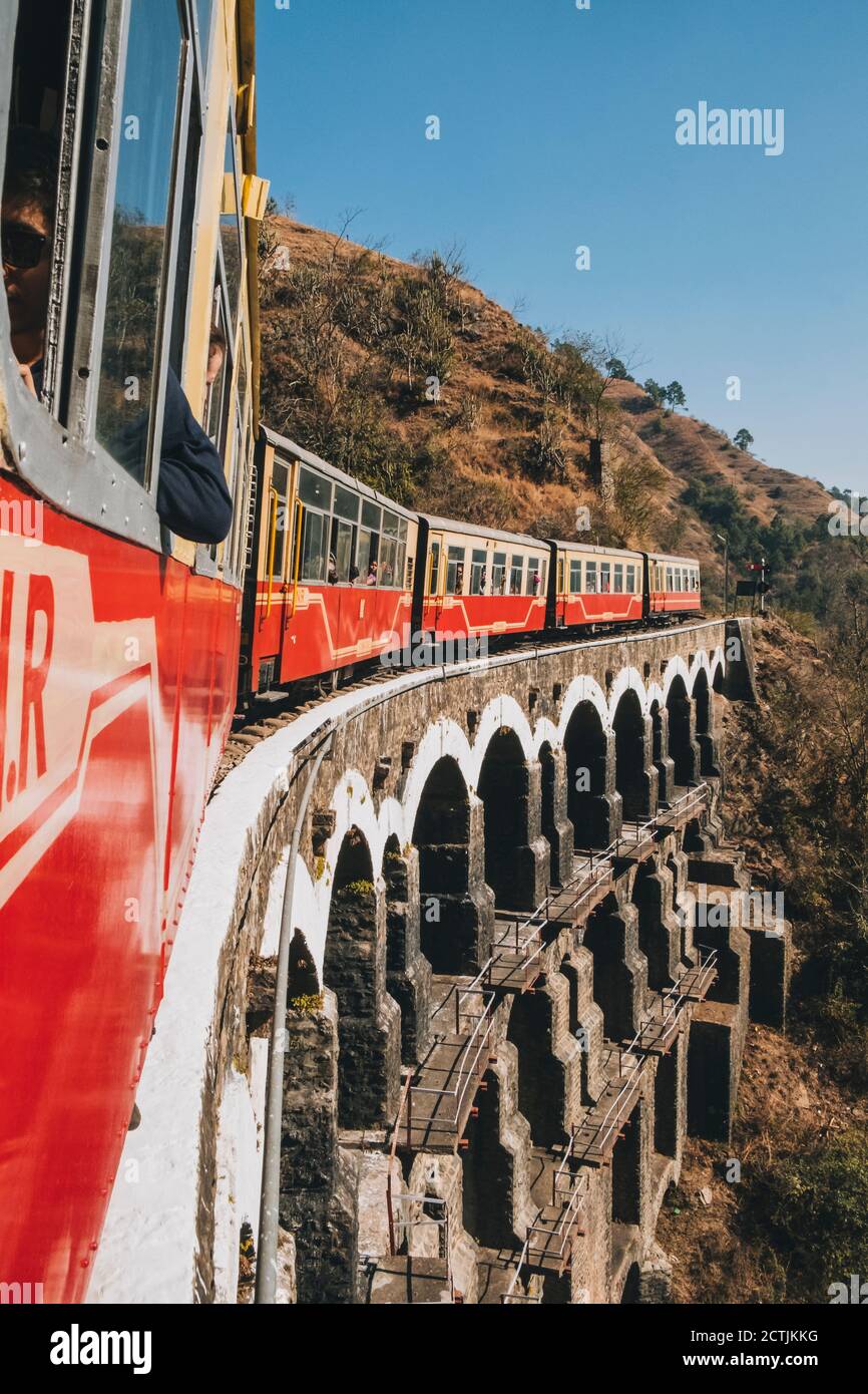 Toy Train passing through an arched bridge in the countryside, from Kalka to Shimla. Stock Photo