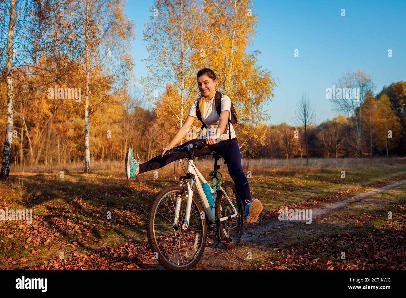 Bicycle ride workout in autumn park. Young woman biker riding a bike in