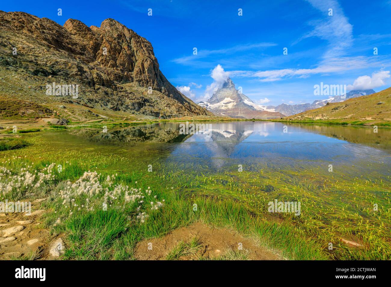 Alpine meadows around Riffelsee Lake with mirror of Mount Matterhorn