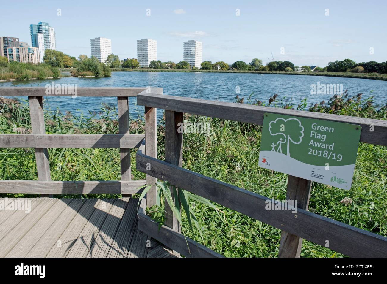 Green Flag Award sign attached to fence with reservoir and tower blocks behind, Woodberry Wetlands urban nature reserve managed by the London Wildlife Stock Photo