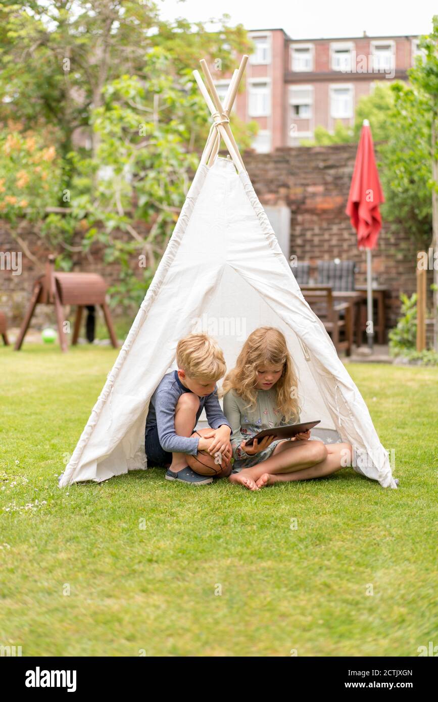 Sisters spending time in a tent on camping. Children using tablet playing games  online during summer vacation - a Royalty Free Stock Photo from Photocase