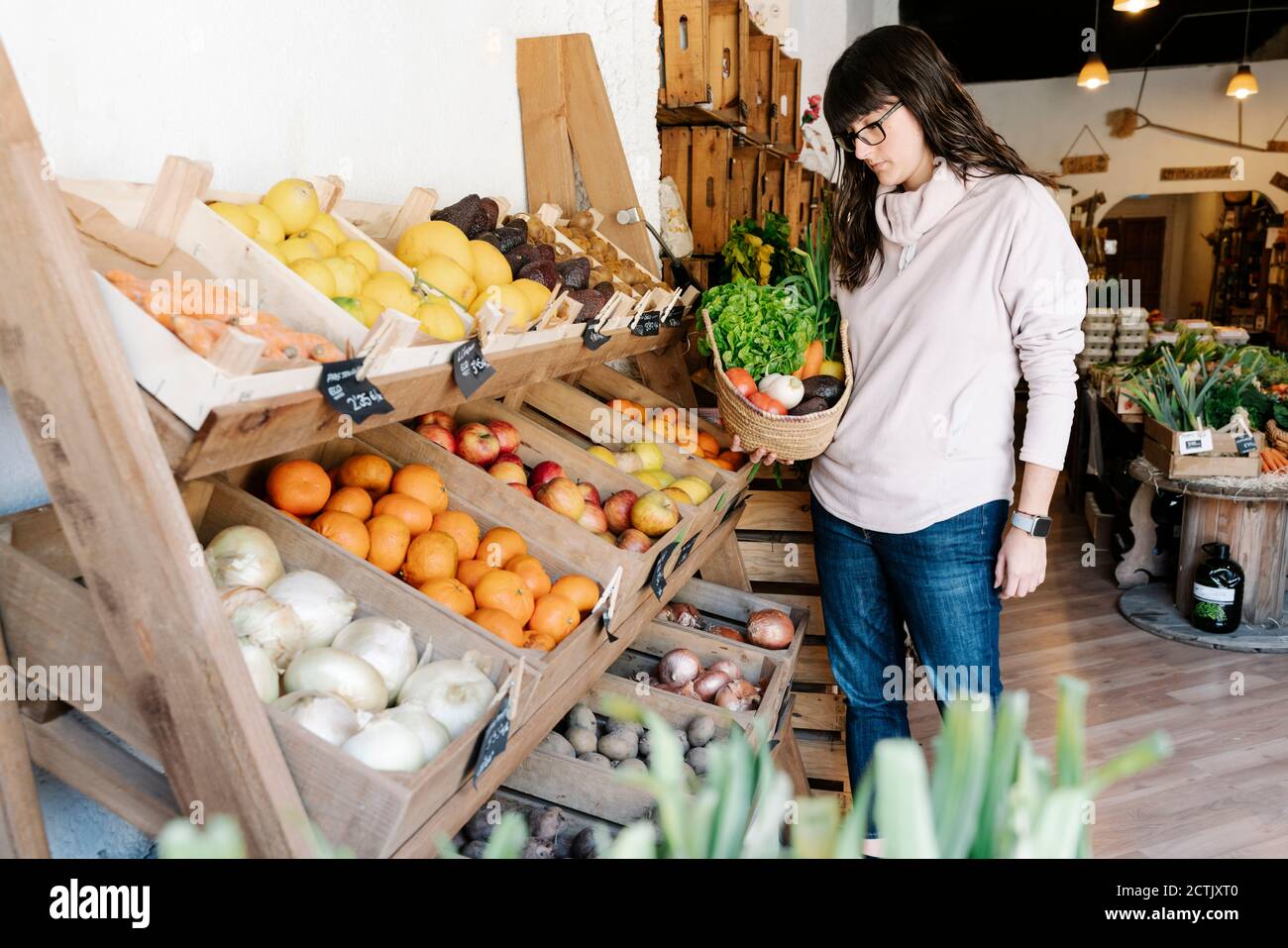 Female customer picking vegetables in basket from grocery store Stock