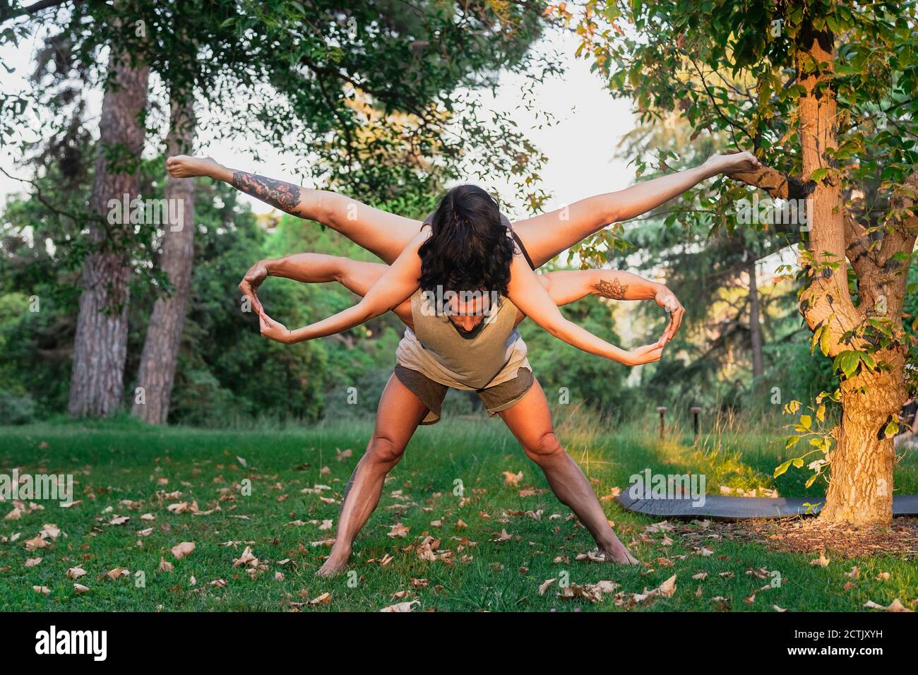 Man balancing woman on back while practicing acroyoga in park Stock Photo