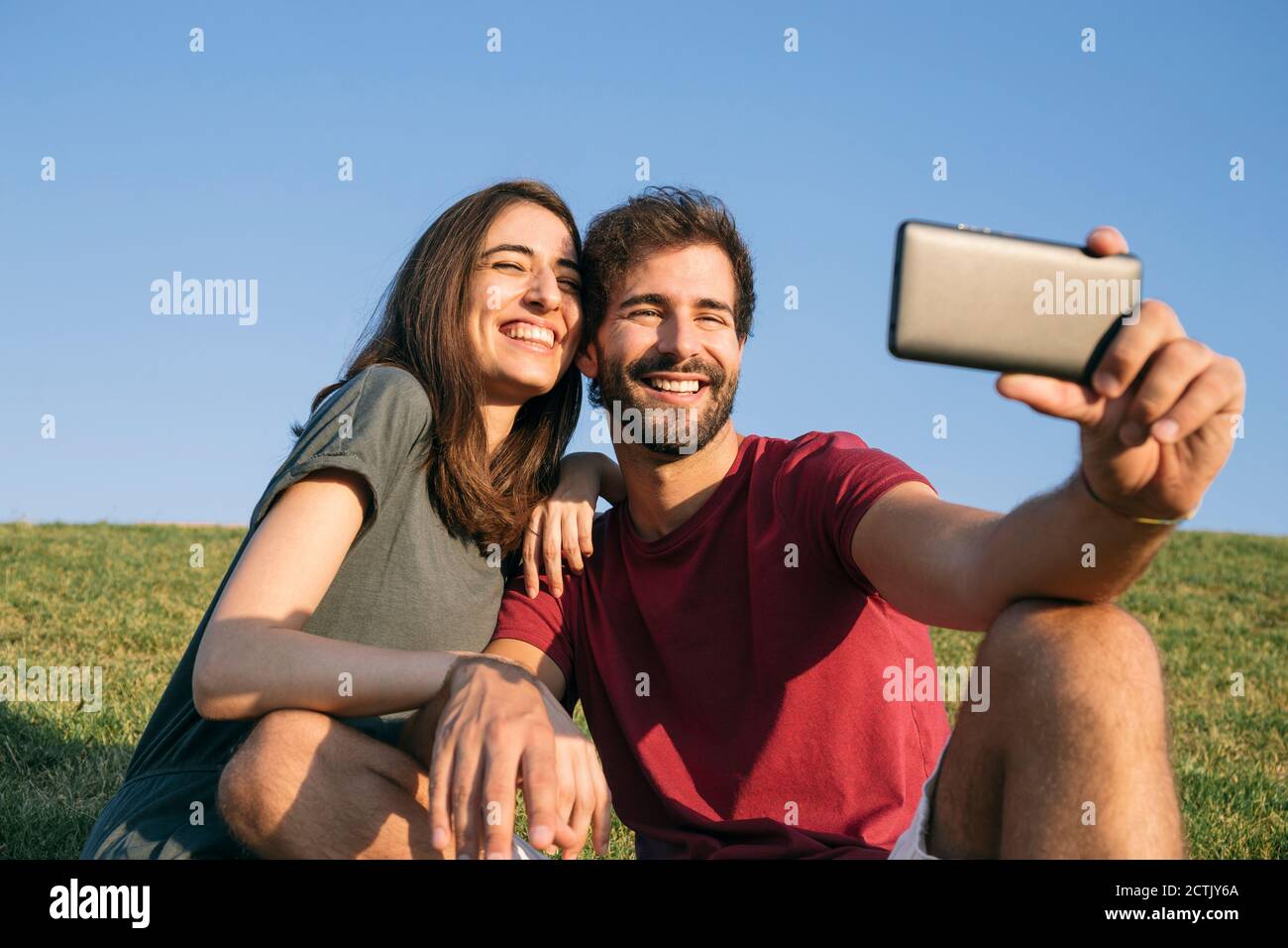 Man taking selfie with woman while sitting on grass Stock Photo