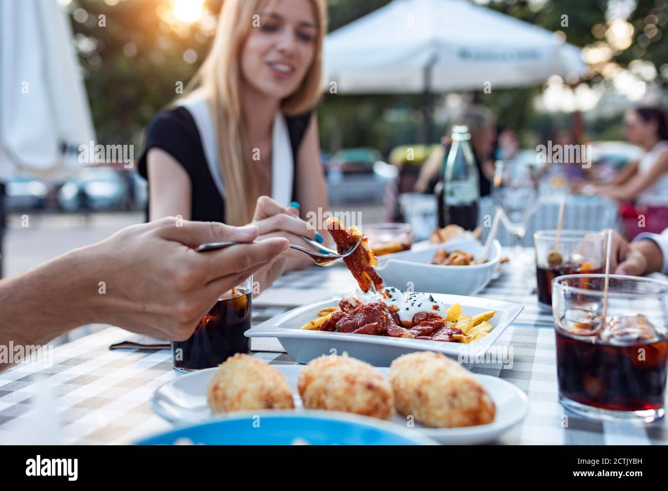 Happy friends having meal while sitting outdoors at cafe Stock Photo