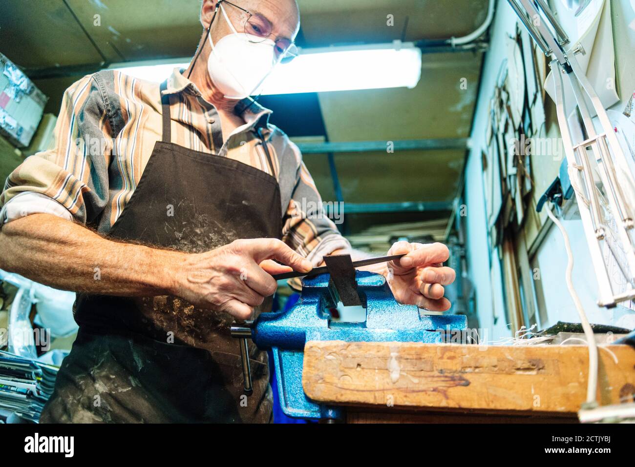 Instrument maker with face mask working at workshop Stock Photo