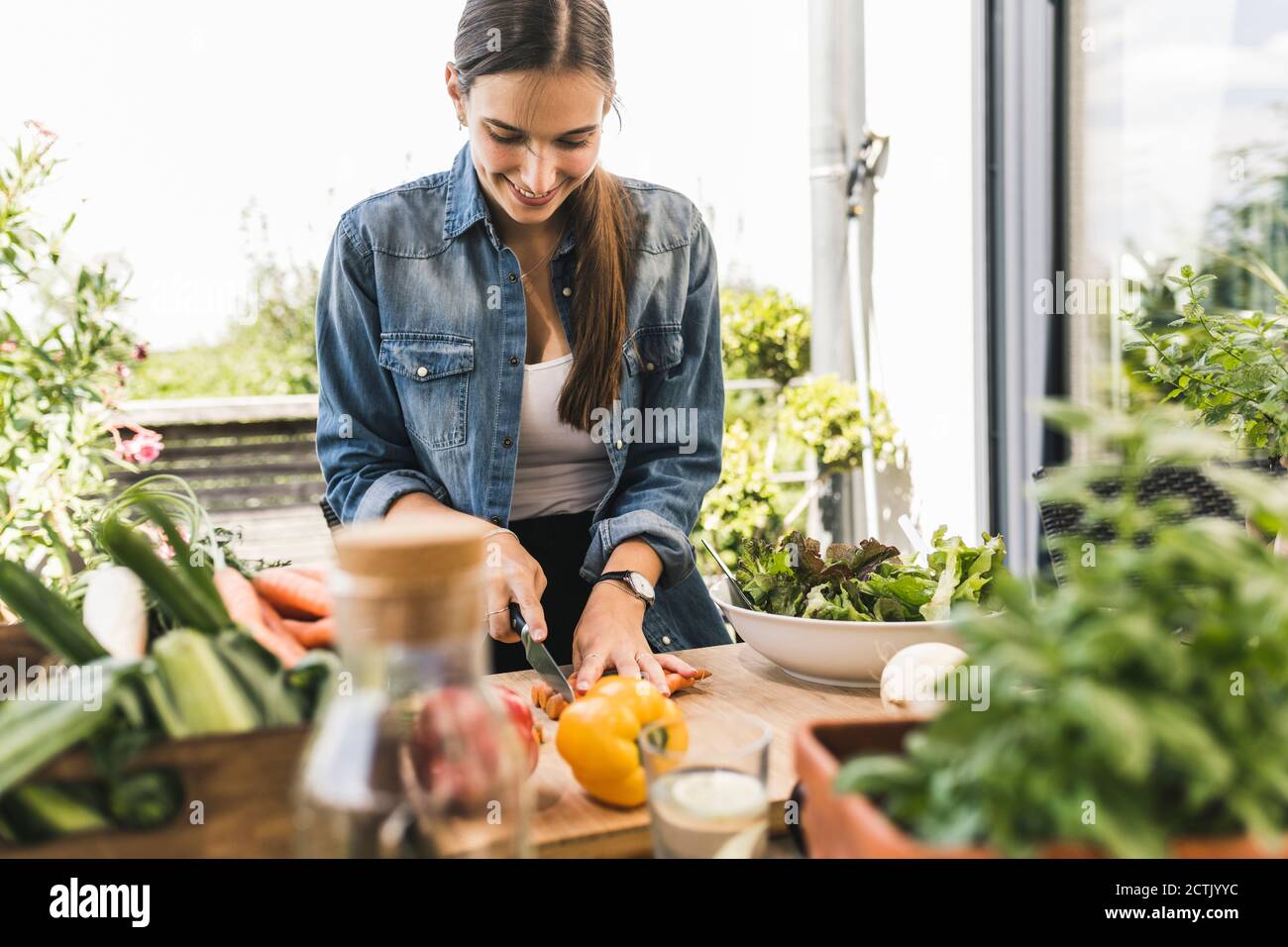 https://c8.alamy.com/comp/2CTJYYC/smiling-young-woman-chopping-vegetables-on-cutting-board-in-yard-2CTJYYC.jpg