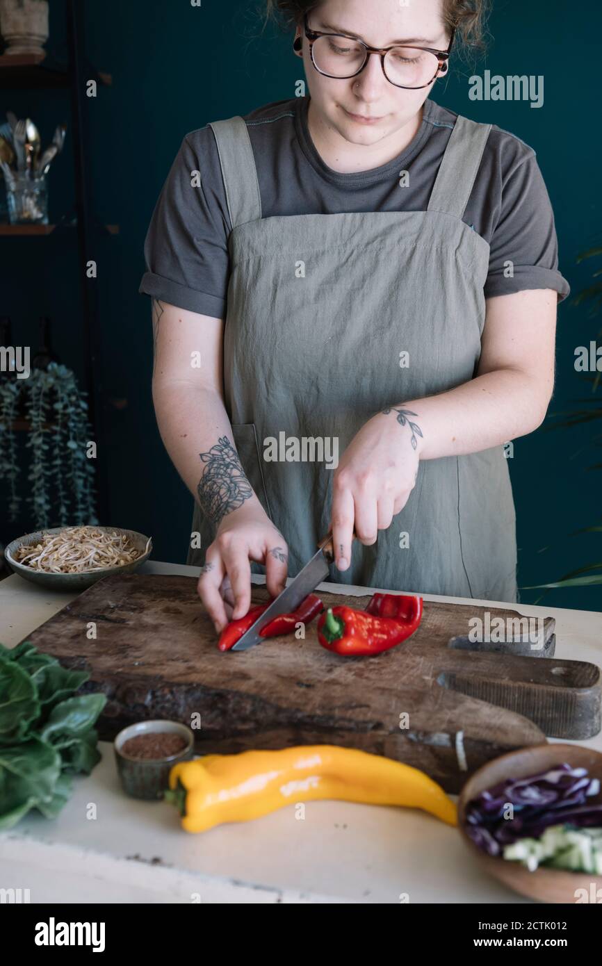 Young woman cutting bell pepper on cutting board Stock Photo