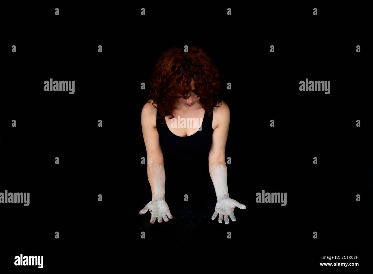 Woman with hands covered with white dust standing against black background Stock Photo