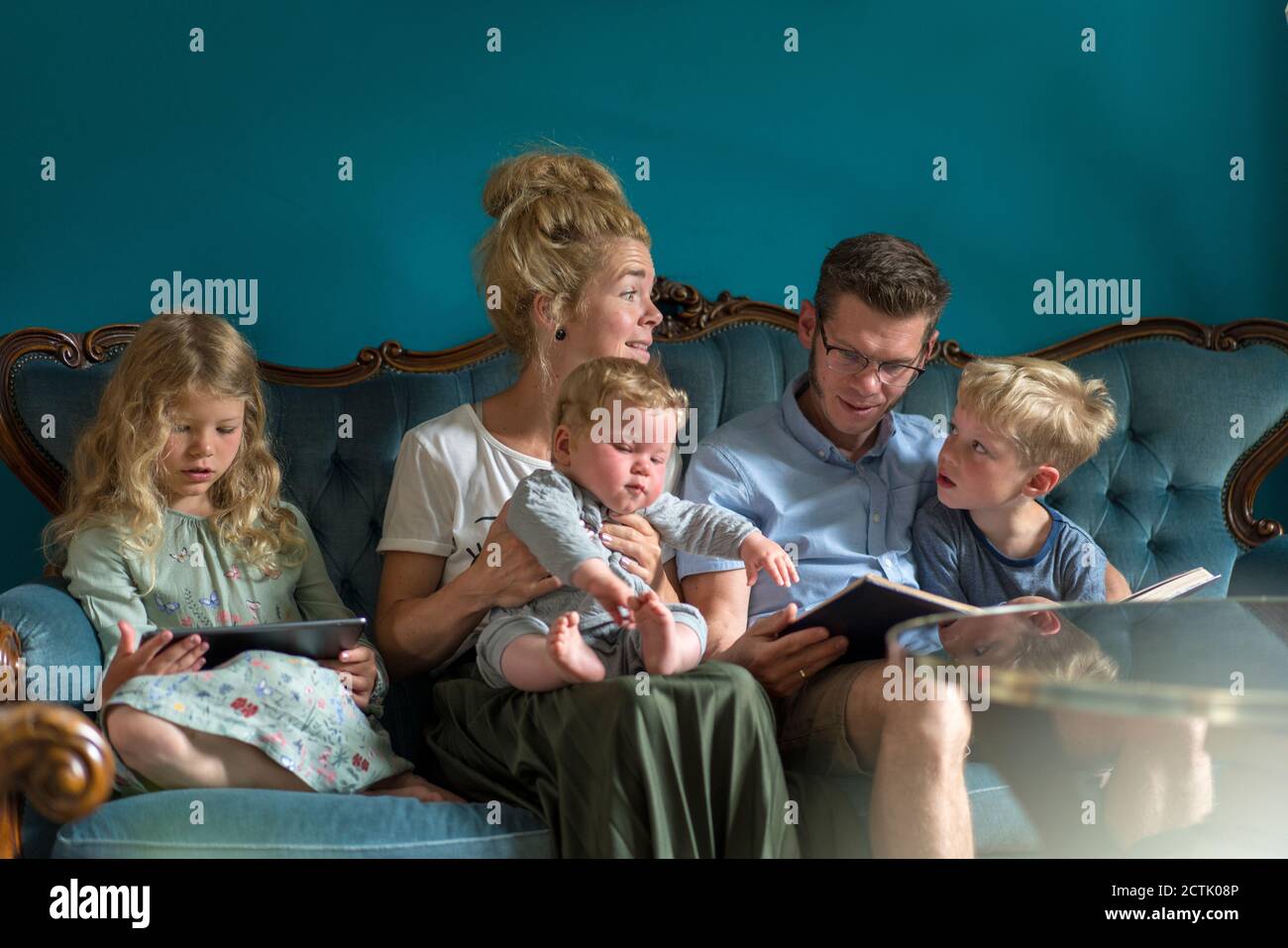 Family sitting on sofa in living room at home Stock Photo - Alamy