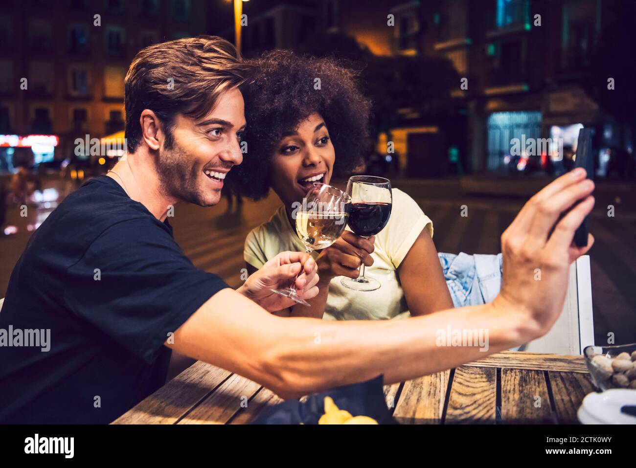 Man taking selfie with girlfriend while toasting wine with her at date night Stock Photo