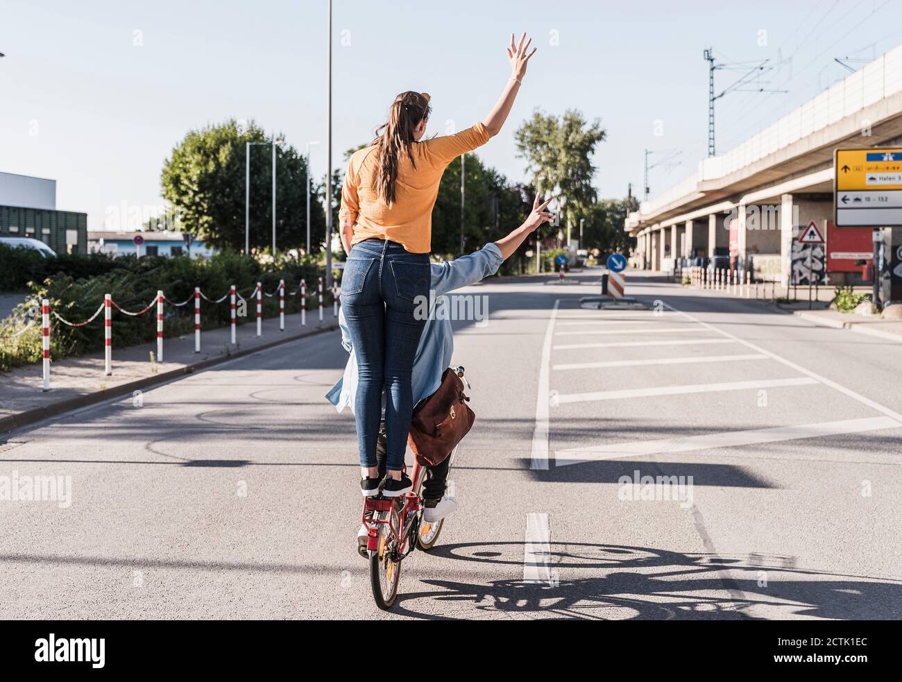 Woman standing behind boyfriend cycling on street in city Stock Photo