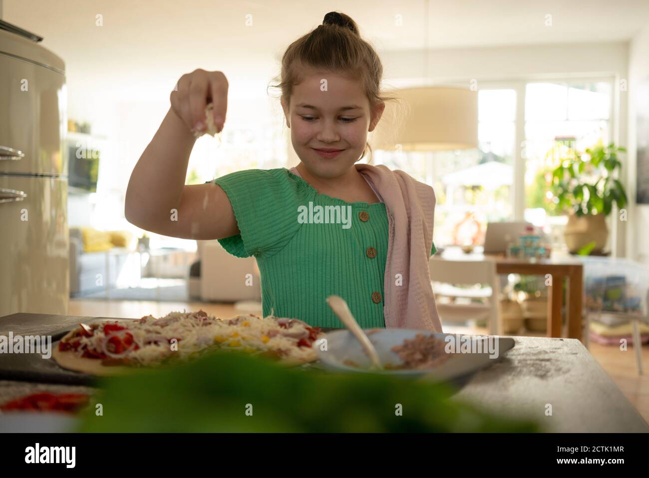 Cute girl preparing pizza with napkin over kitchen island Stock Photo