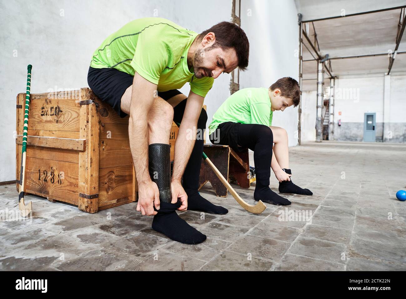 Mature man and son wearing socks while sitting on wooden box at court Stock Photo