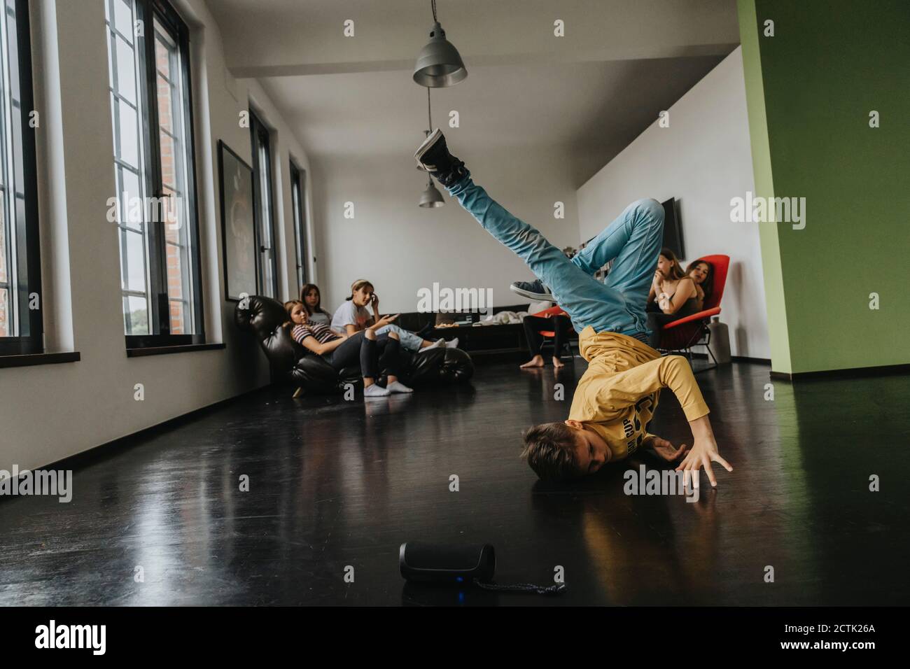 Friends looking at boy breakdancing on floor Stock Photo