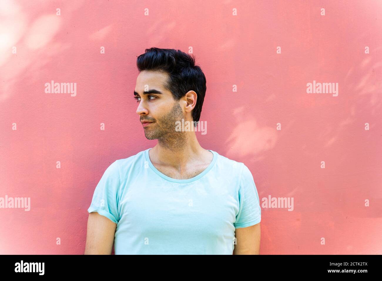 Thoughtful man looking away against wall Stock Photo