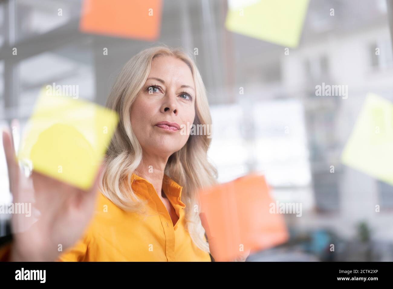 Close-up of female professional planning over adhesive notes stuck on window in home office Stock Photo