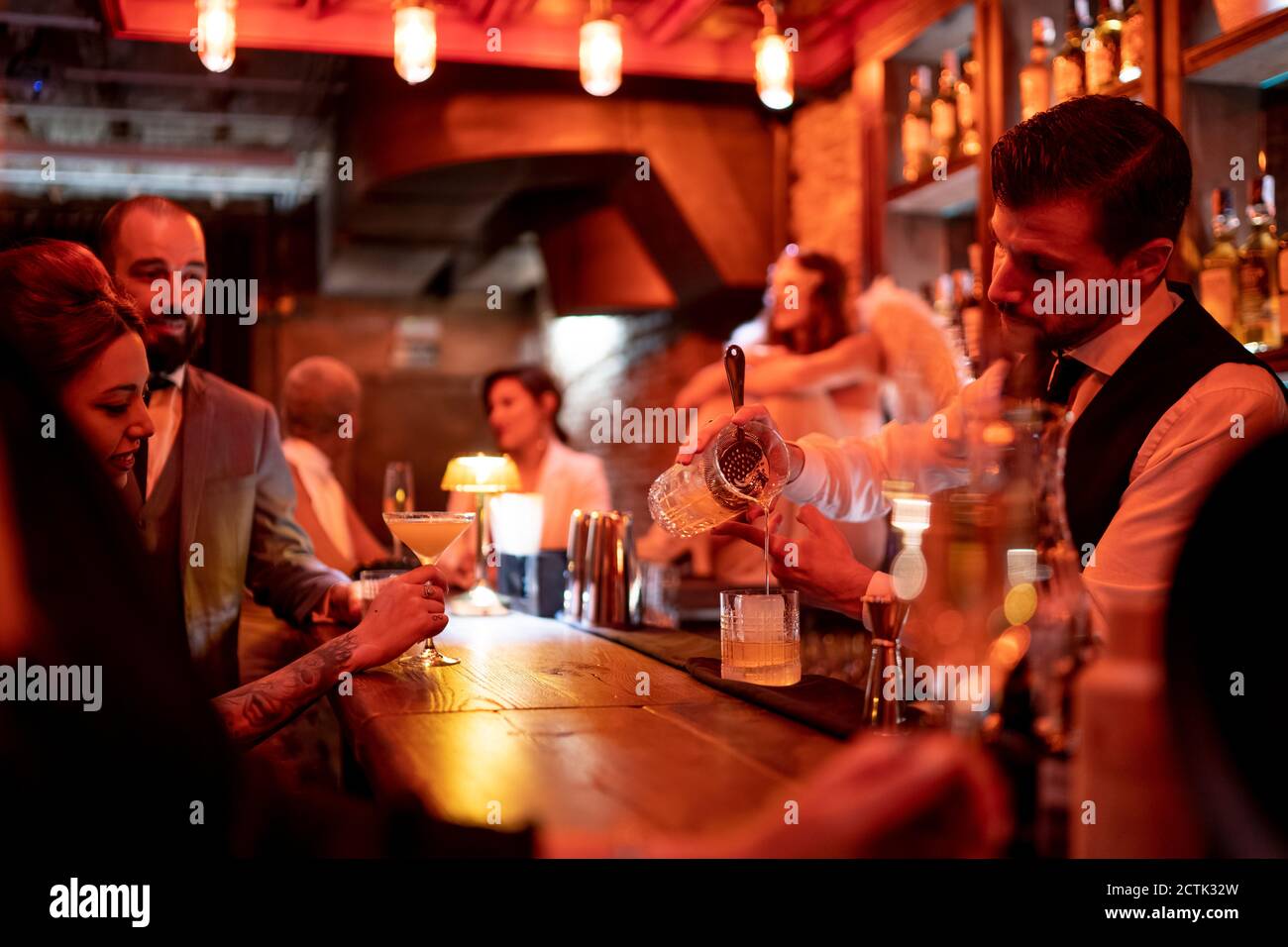 Bartender serving drink while standing at bar counter in pub Stock