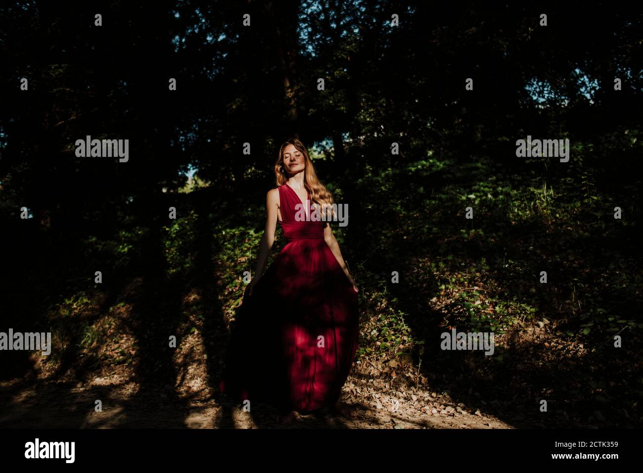 Thoughtful woman standing in forest Stock Photo