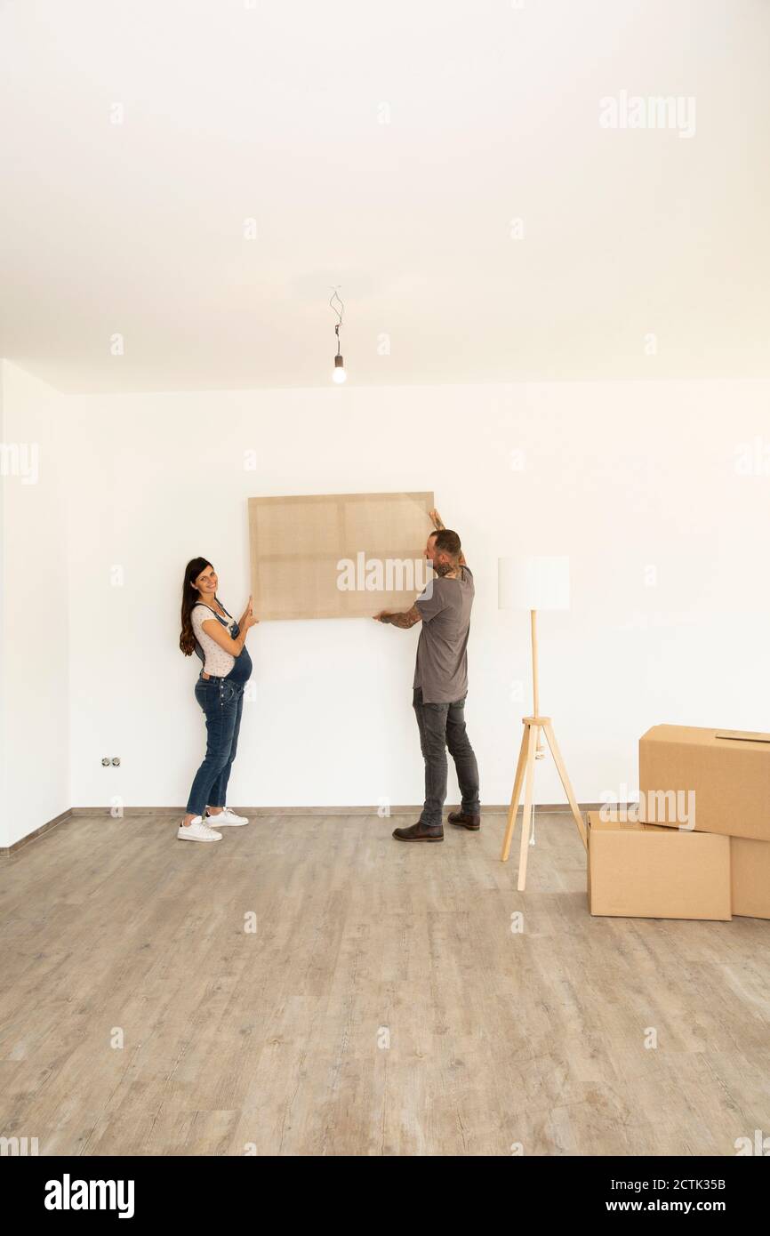Pregnant woman with husband carrying window frame while standing in new