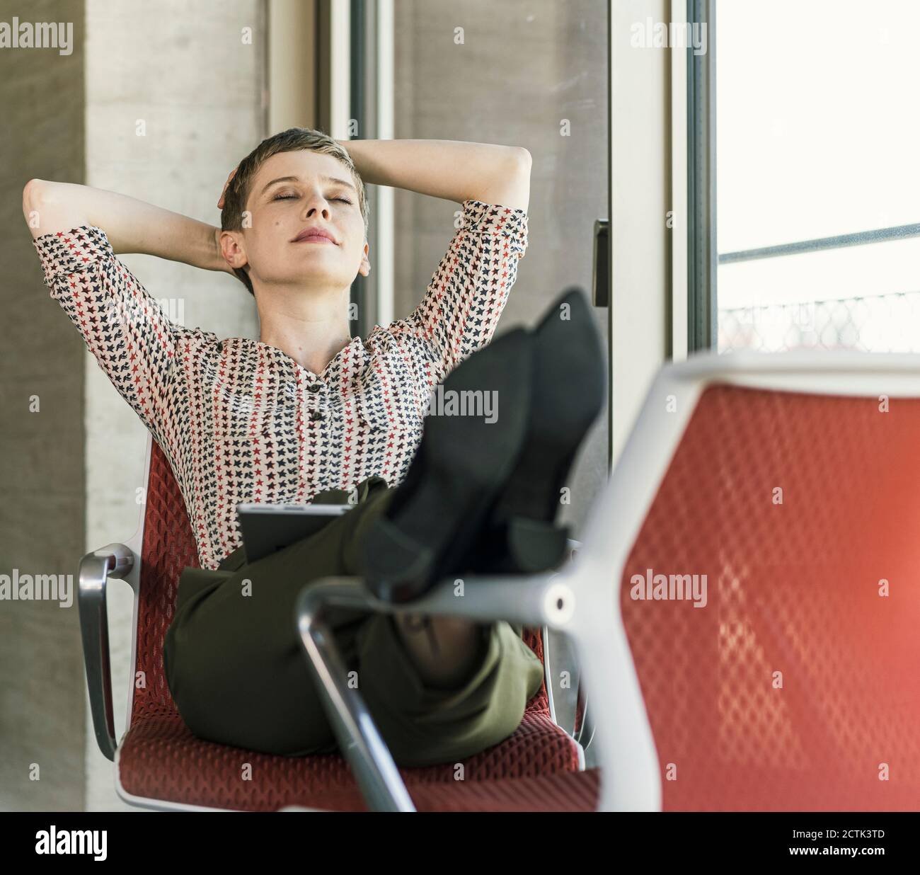 Relaxed businesswoman with closed eyes sitting on chair in office ...