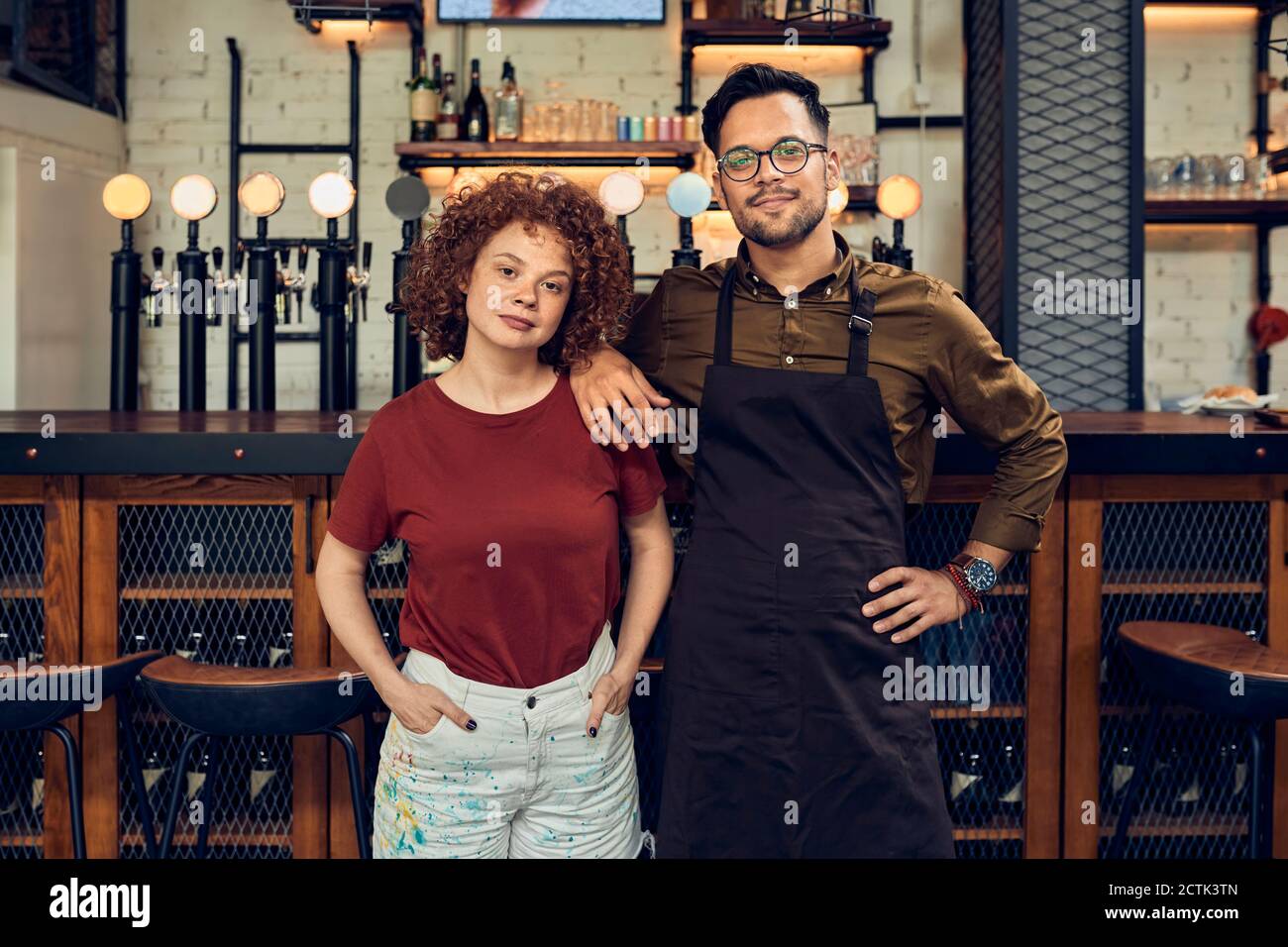 Portrait of confident owner couple at the counter in a pub Stock Photo