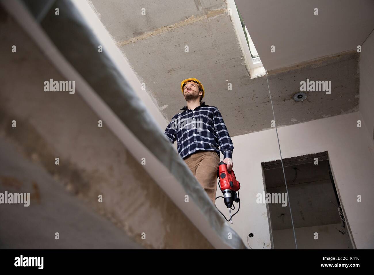 Construction worker holding power tool while walking in renovating house Stock Photo