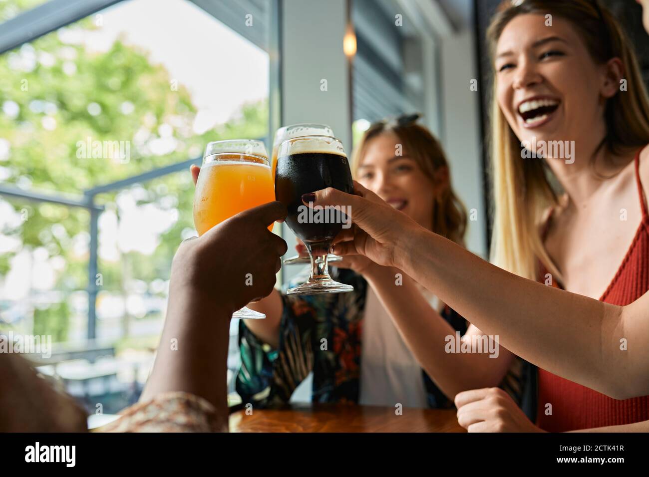 Happy female friends clinking craft beer glasses in a pub Stock Photo