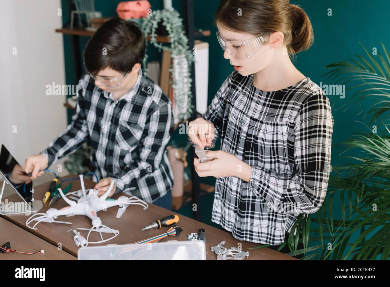 Siblings using digital tablet while preparing drone on table at home Stock Photo