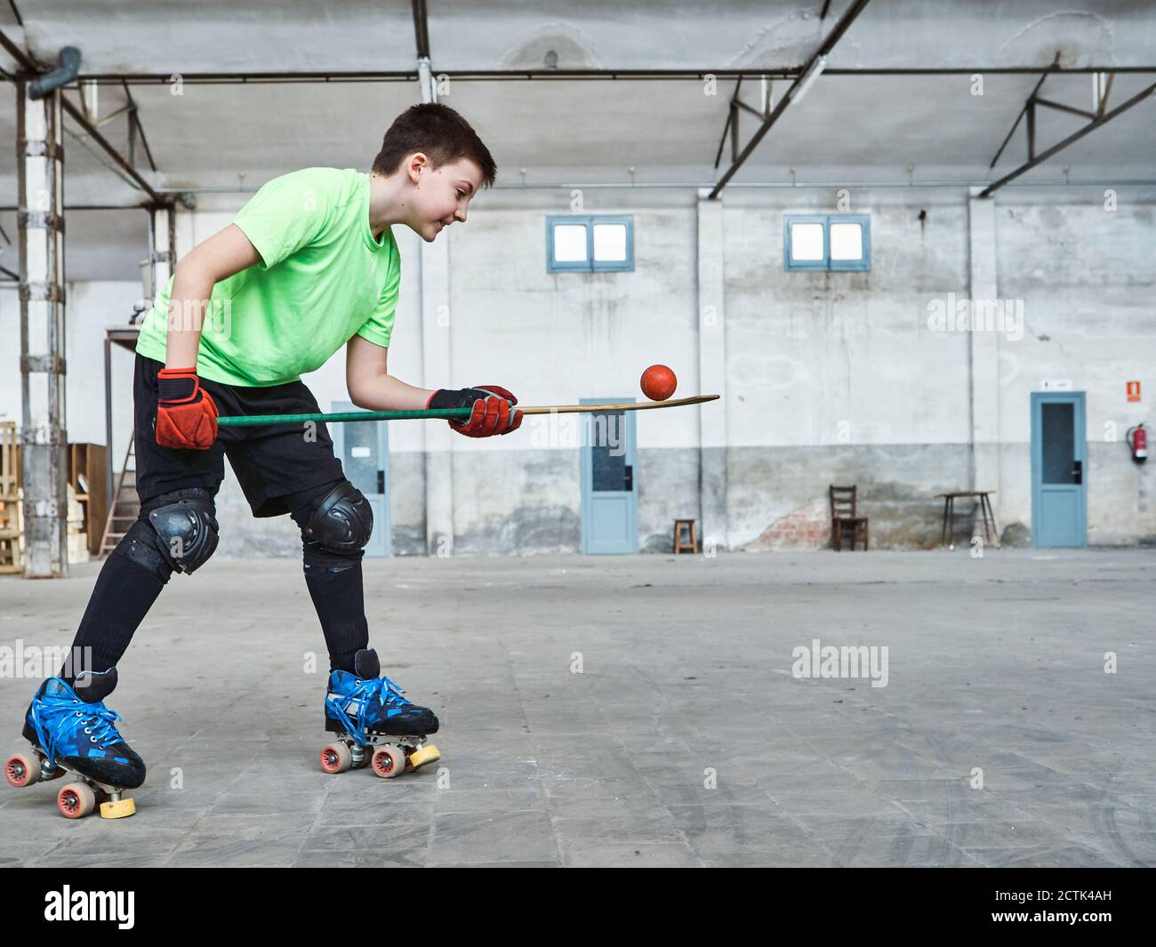 Boy balancing ball on hockey stick during training at court Stock Photo ...
