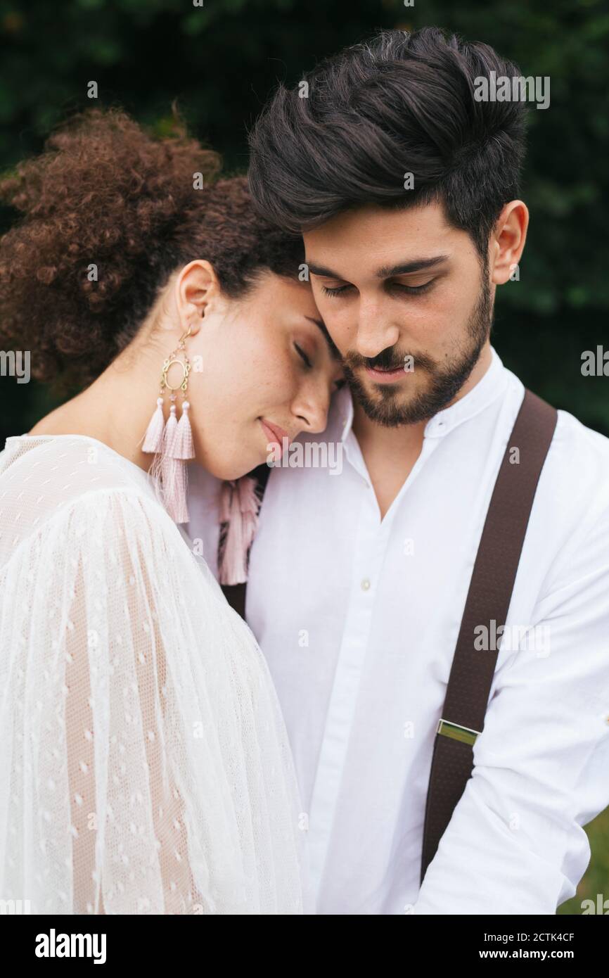 Young woman embracing man while standing at garden Stock Photo - Alamy