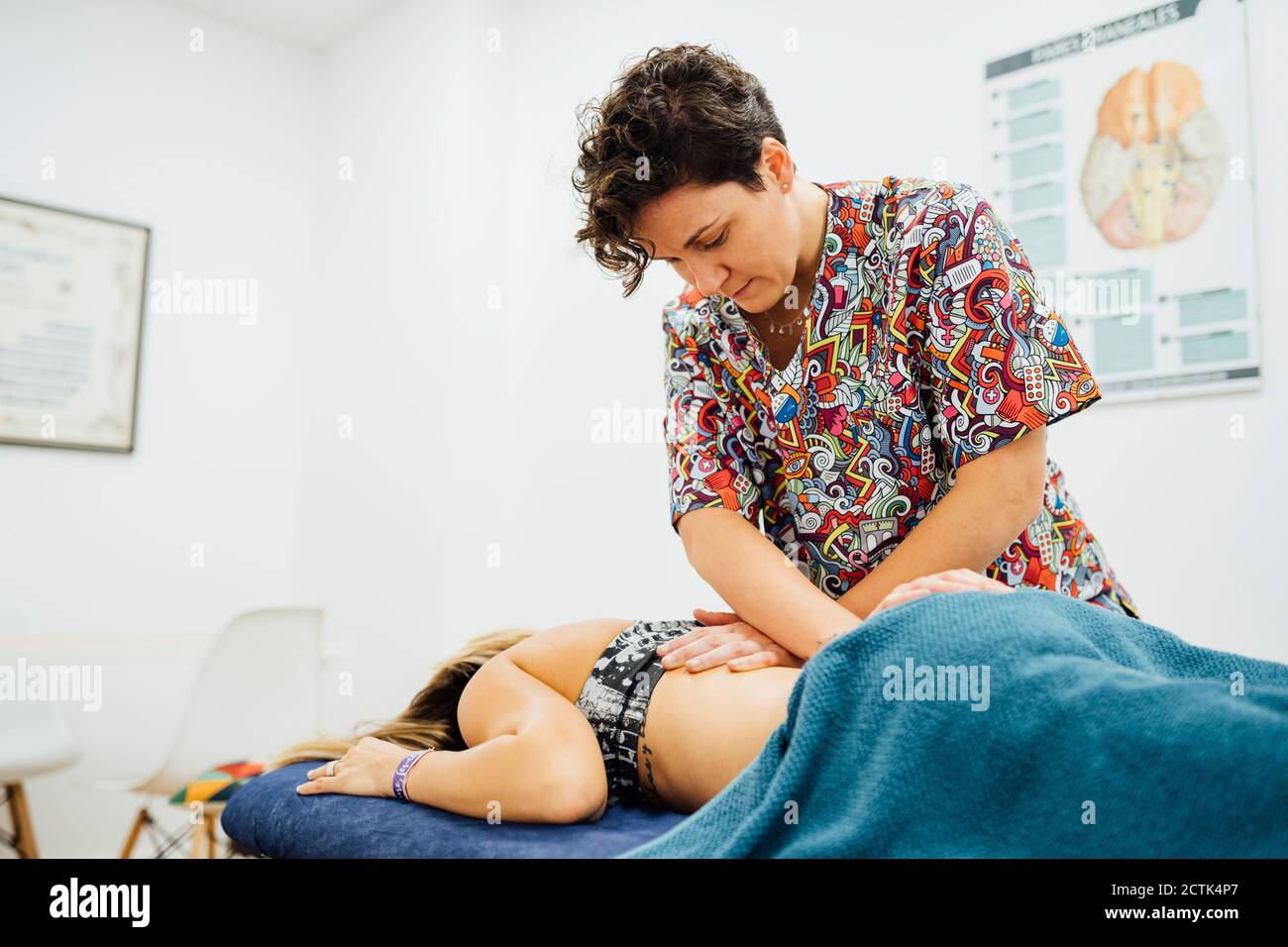 Female osteopath therapist giving back massage to sportswoman at health spa Stock Photo