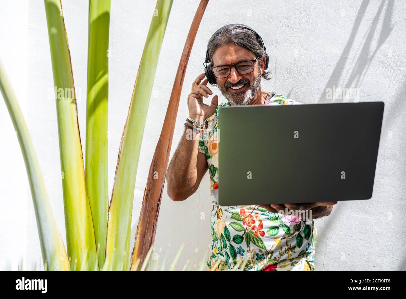 Smiling man using laptop while standing by Stock Photo