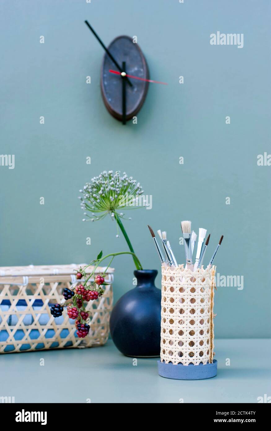 Vase with flowers and DIY rattan desk organizer with paintbrushes Stock Photo