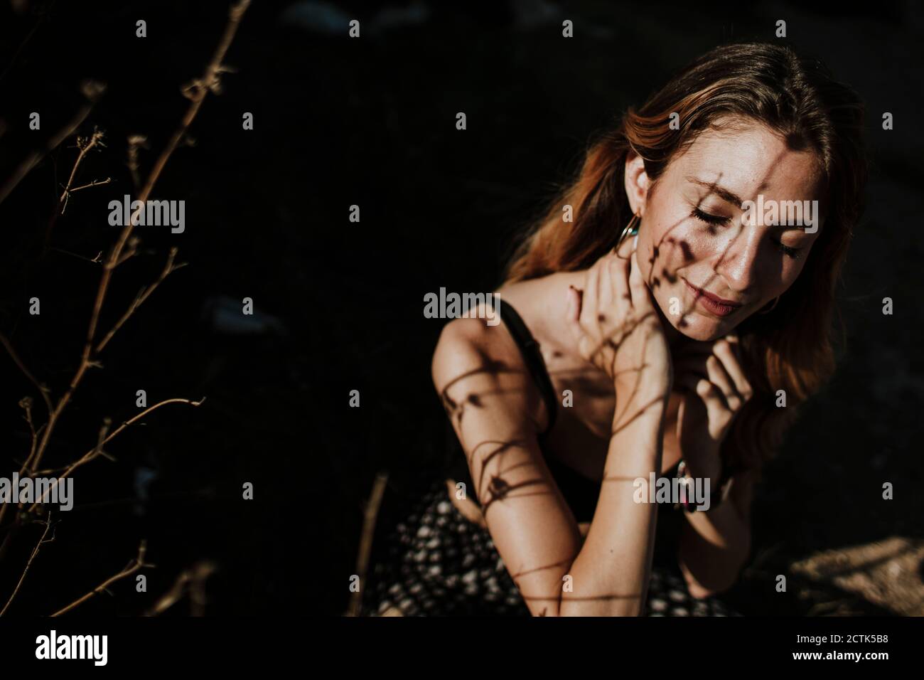Woman sitting eyes closed in forest under sunlight Stock Photo - Alamy
