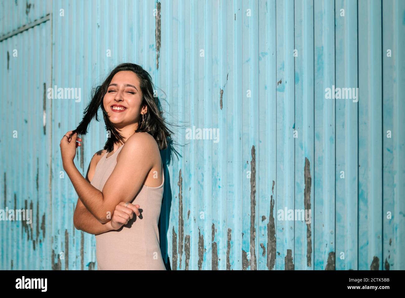 Portrait of happy brunette young woman standing at a run down wall Stock Photo