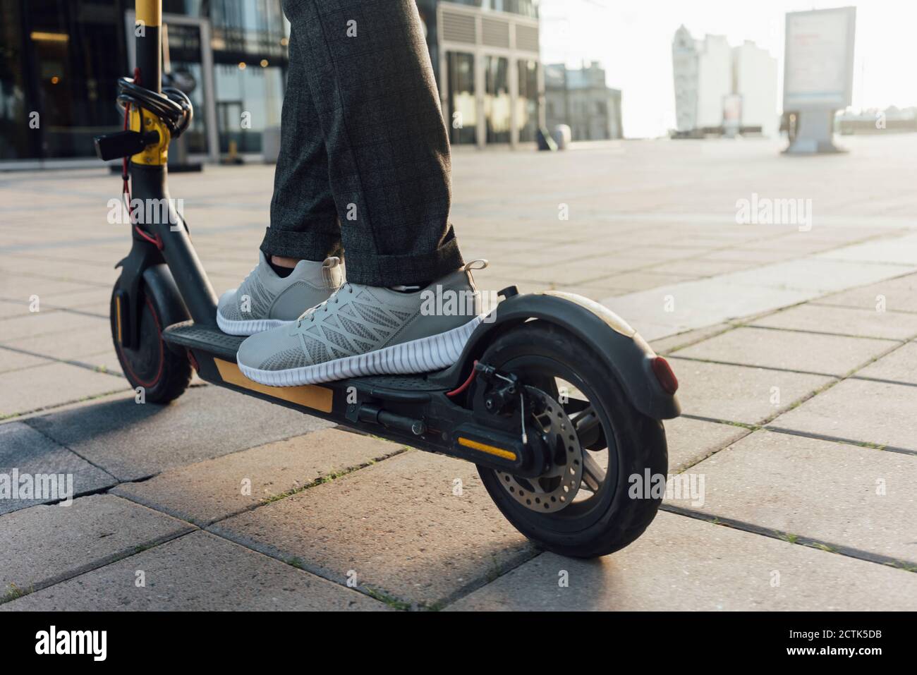 Low section of businessman riding electric push scooter at downtown