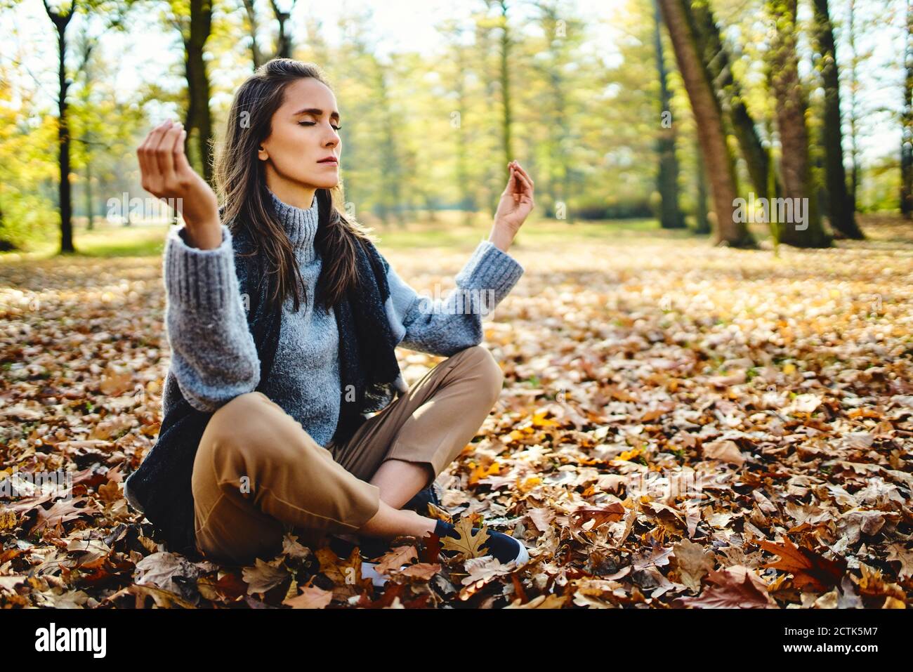 Young woman meditating in autumn forest Stock Photo