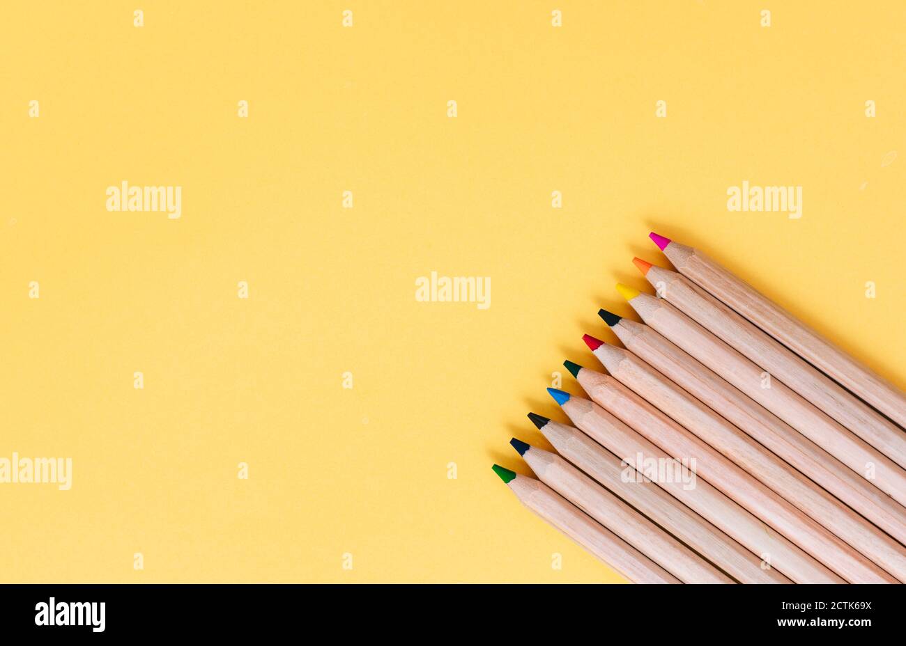 Colored pencils arranged on yellow background Stock Photo