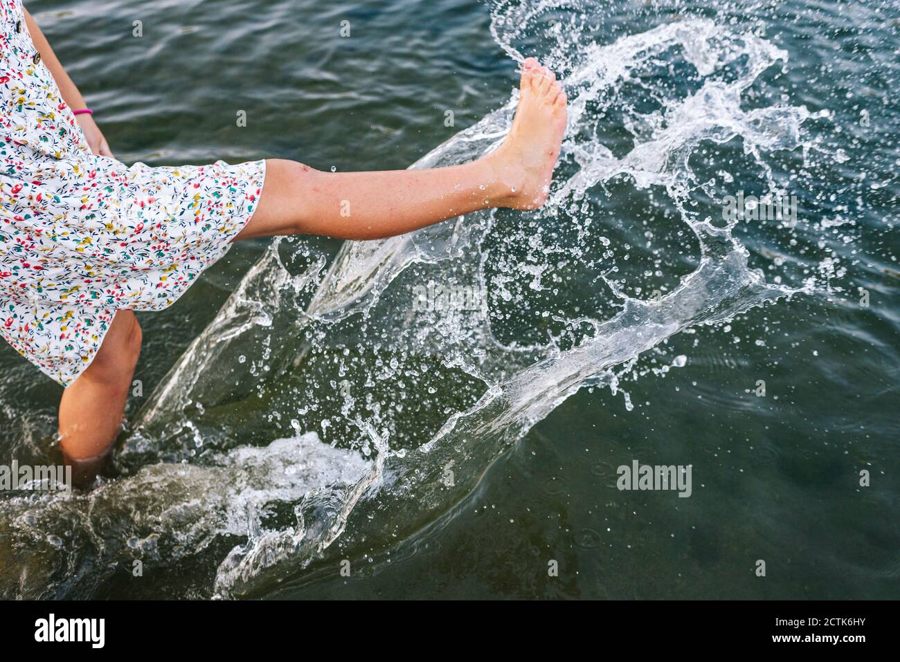 Girl splashing water with legs in lake Stock Photo - Alamy