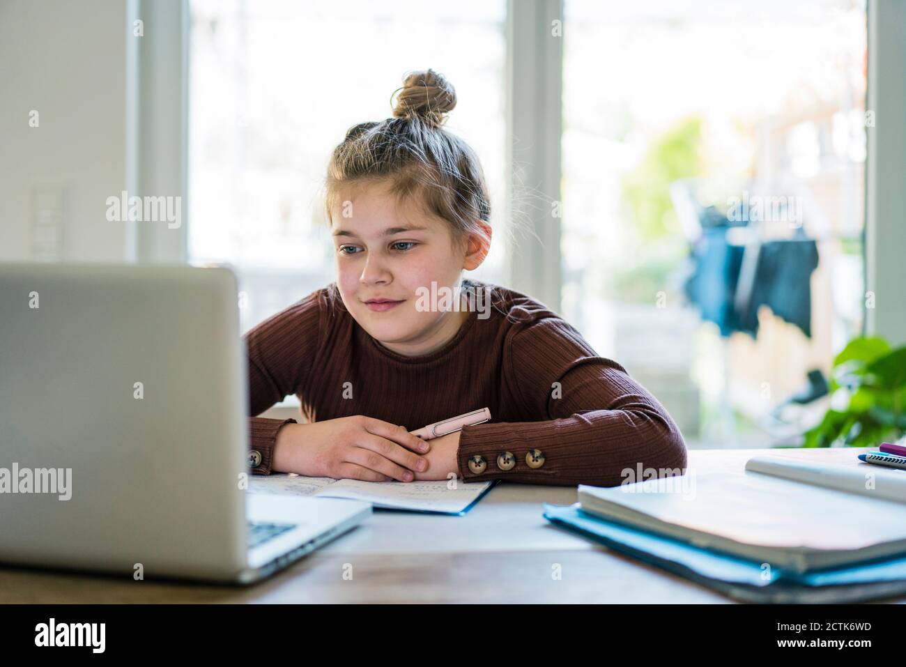 Girl with book using laptop while studying at home Stock Photo - Alamy