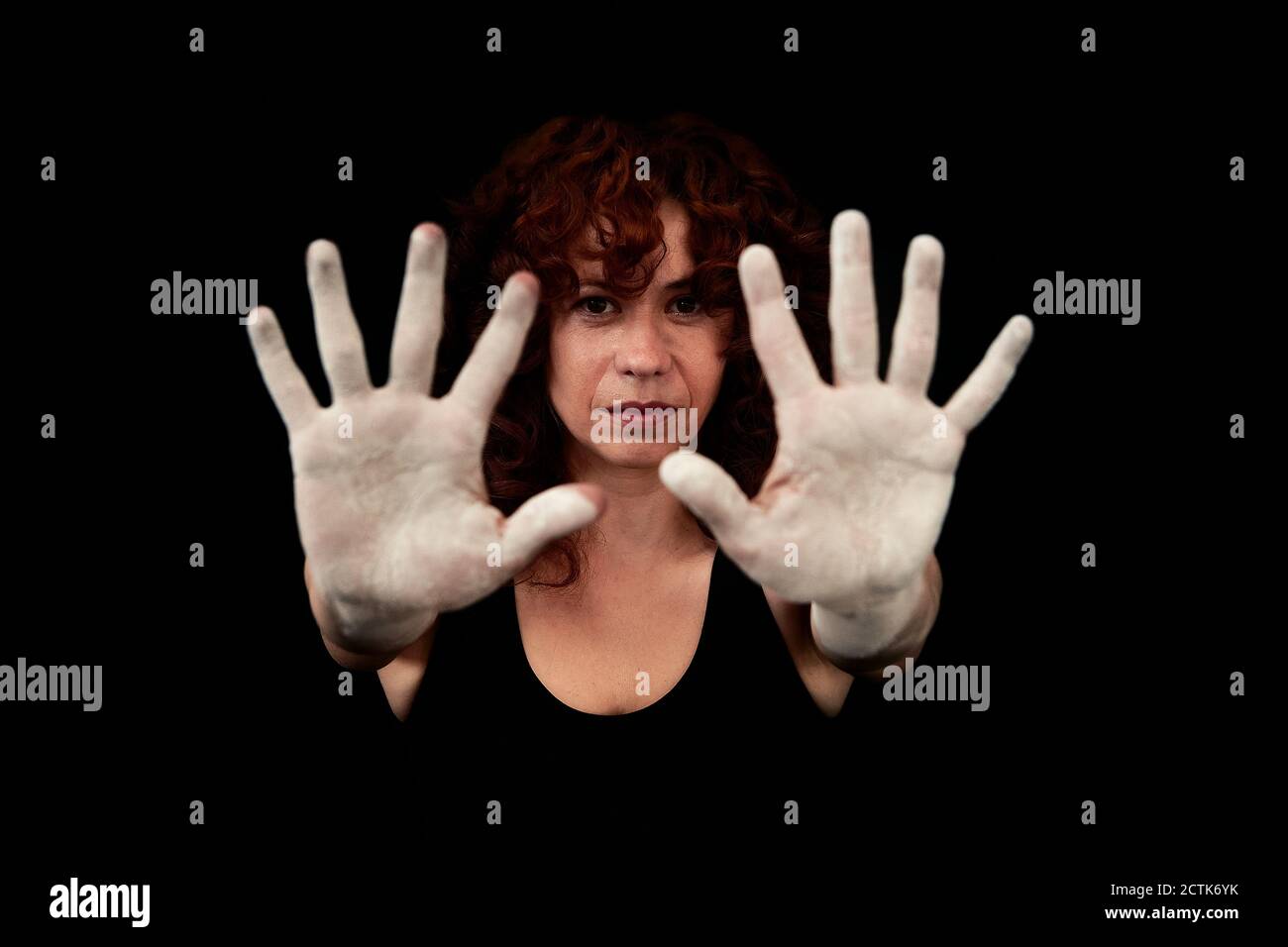 Close-up of women hands covered with white dust standing against black background Stock Photo