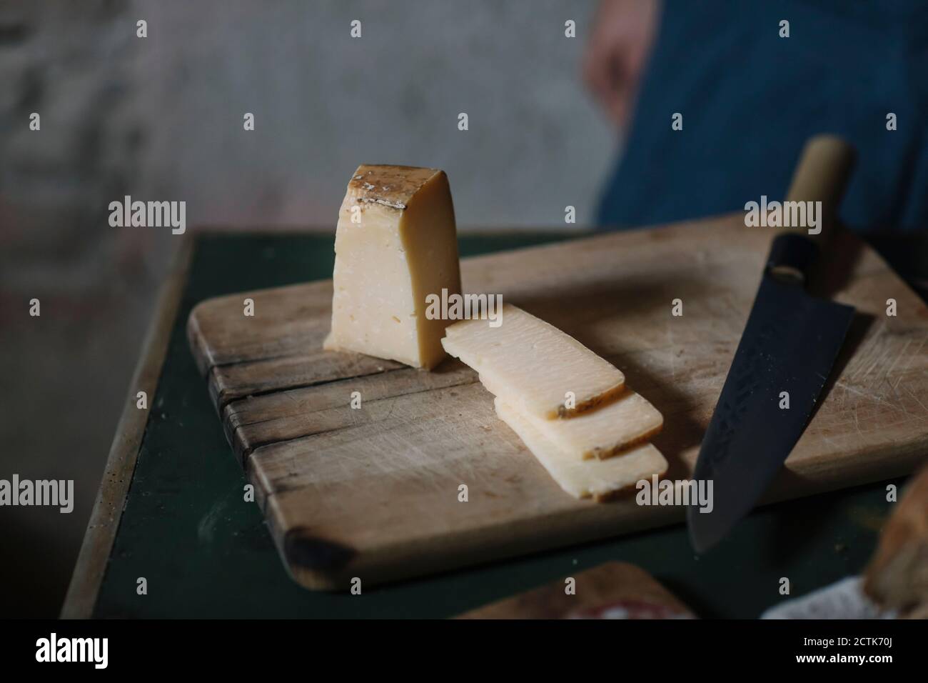 Close-up of artisanal cheese slices with knife on cutting board Stock Photo