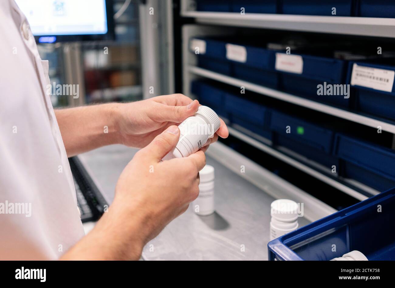 Close-up of male doctor holding medicine bottle at table in pharmacy Stock Photo